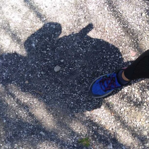 l'ombra di una donna e il suo piede mentre si appoggia sull'asfalto