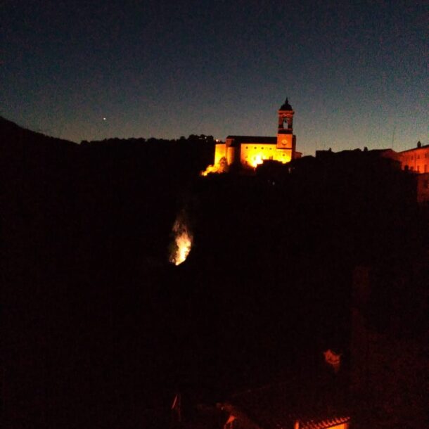 panorama notturno, una chiesa illuminata sopra un monte si staglia su un cielo stellato
