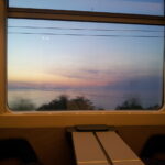 Panorama marino inquadrato dal finestrino di un treno