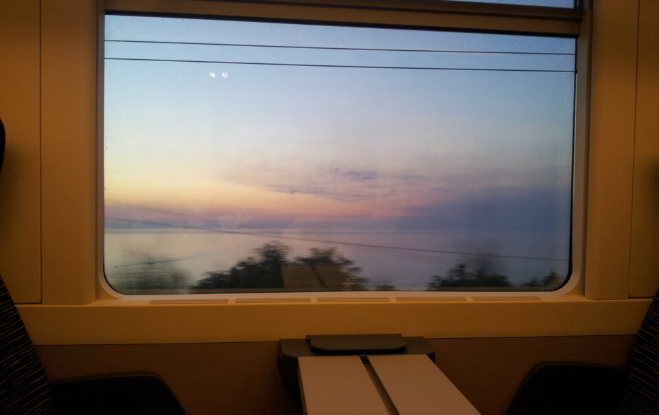 Panorama marino inquadrato dal finestrino di un treno