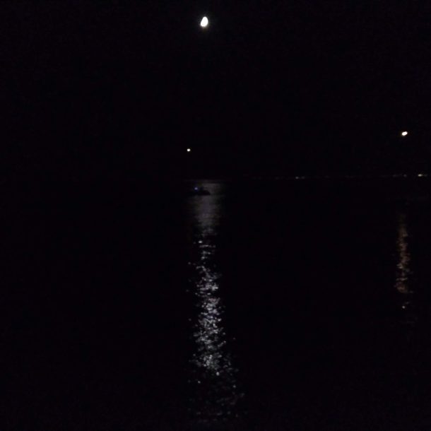 nel buio una luce fioca della luna si riflette sul mare