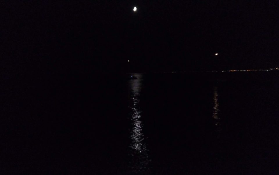 nel buio una luce fioca della luna si riflette sul mare