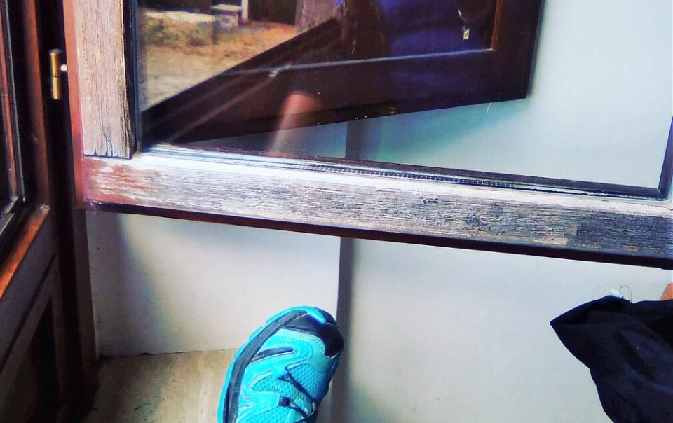 scarpe da trekking in evidenza davanti a uno specchio dove è riflessa l'immagine di una donna